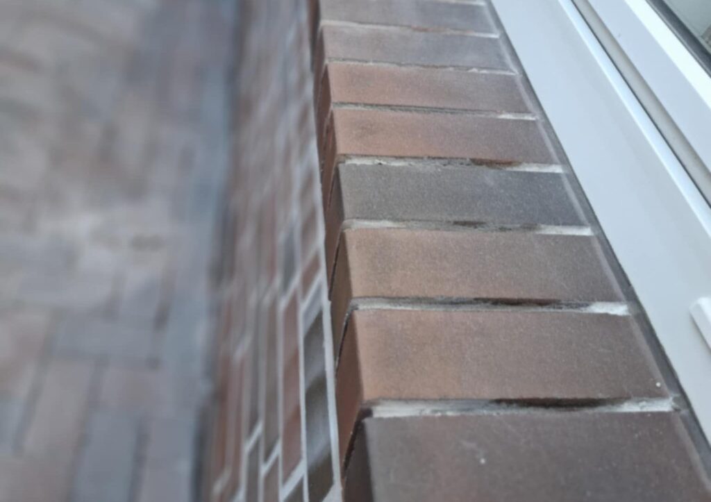 Detailaufnahme präziser Fugenarbeiten an einem Fensteranschluss mit Klinkerfassade