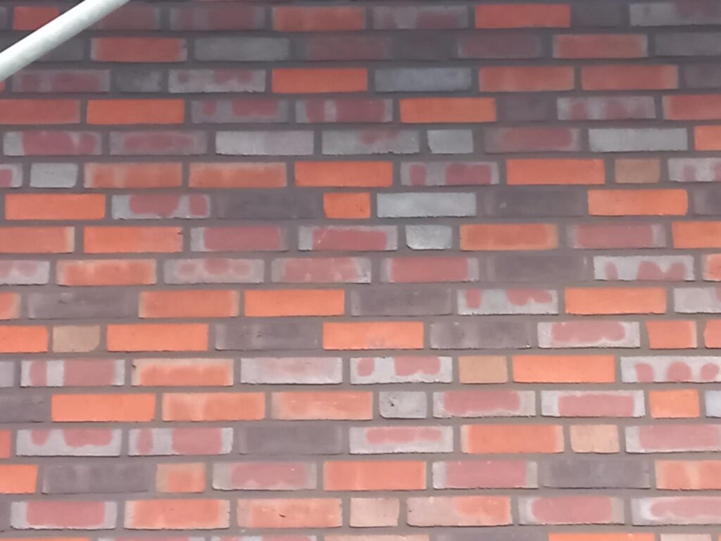 Fugenarbeit an einer rot-braunen Klinkerwand mit markanter Farbstruktur